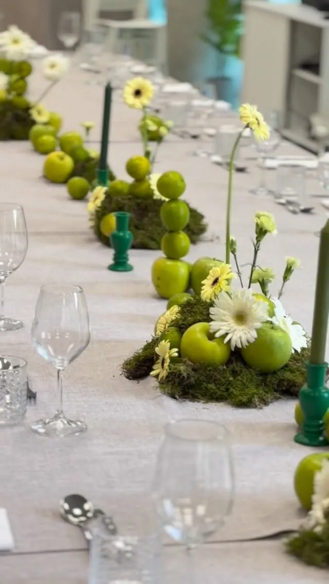 Mesa imperial con manzanas verdes, musgo, gerberas blancas y velas verdes para Mujer Hoy