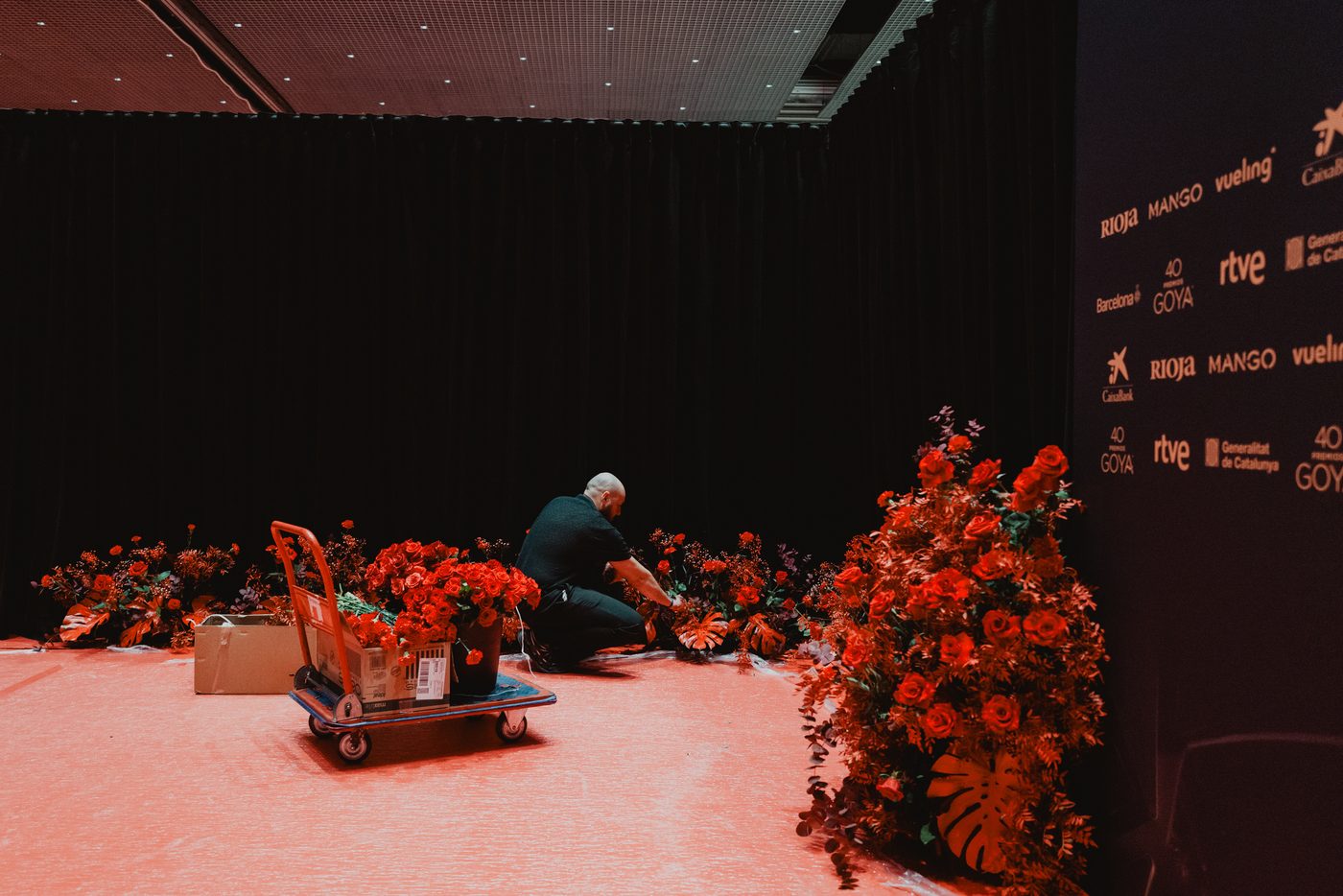 Floristas de Les Fleurs colocando composiciones rojas junto al photocall de los Premios Goya