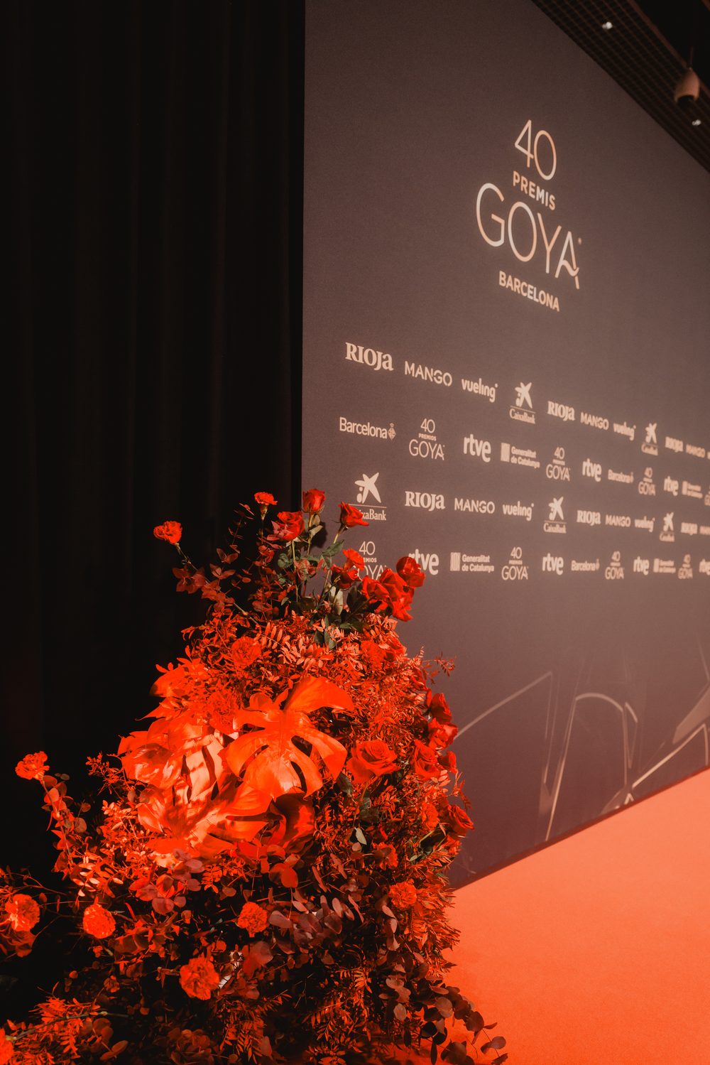 Composición de flores rojas y hojas de monstera junto al photocall de los 40 Premios Goya en Barcelona