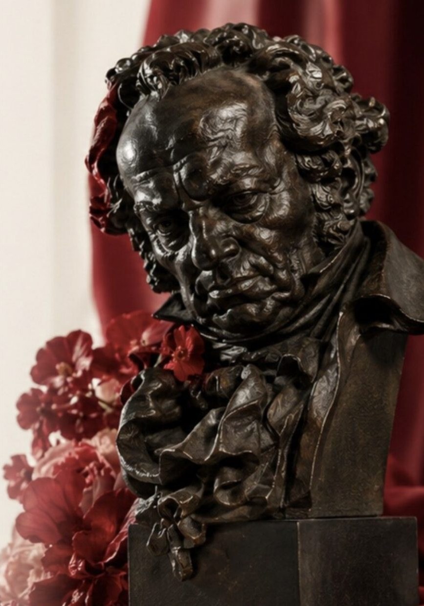 Estatuilla de los Premios Goya con flores rojas