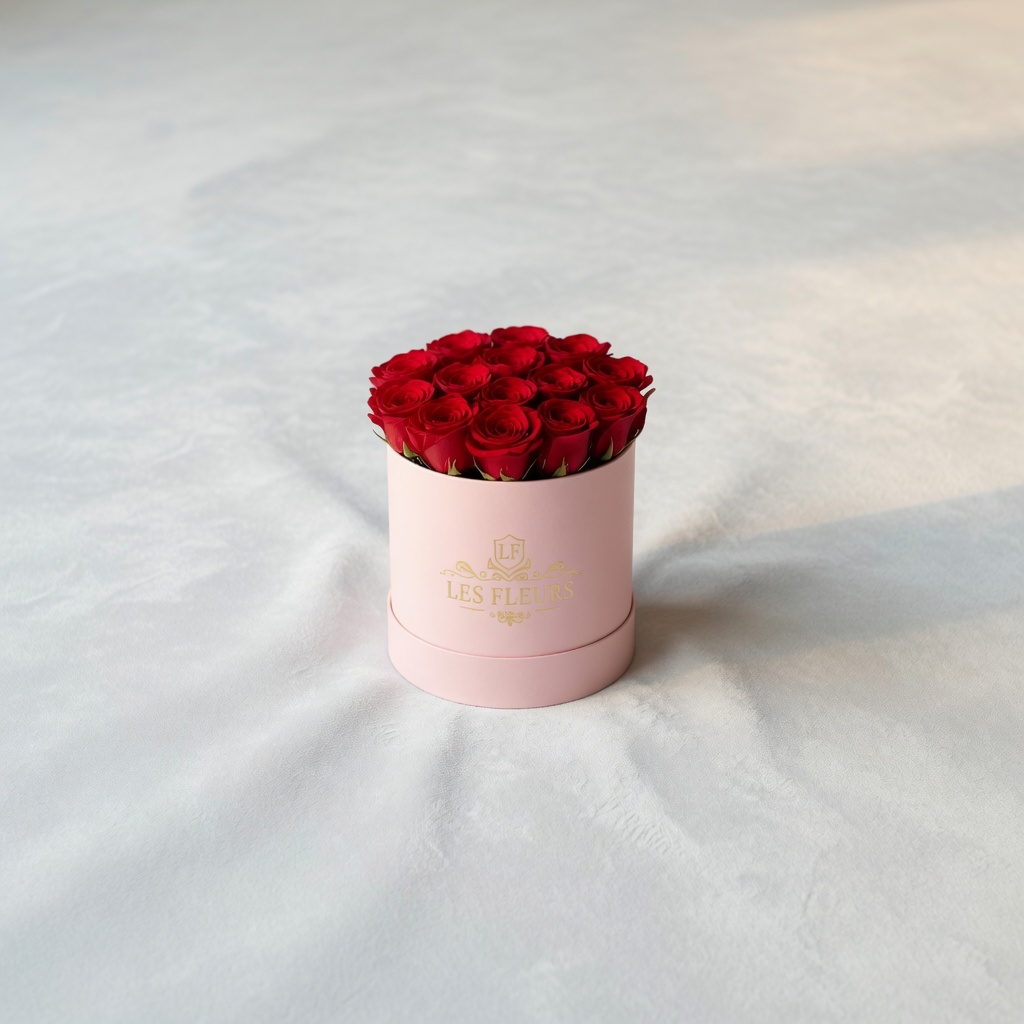 Pink cylindrical gift box filled with a bouquet of red roses on a pale, textured surface.
