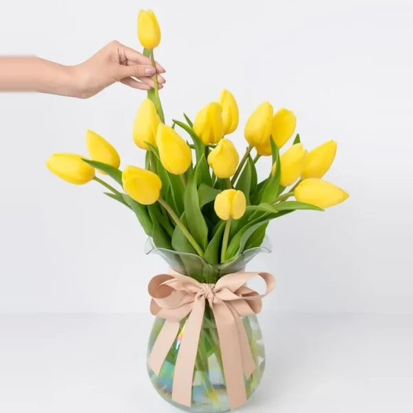 Quince tulipanes amarillos en jarrón de cristal con lazo color crema